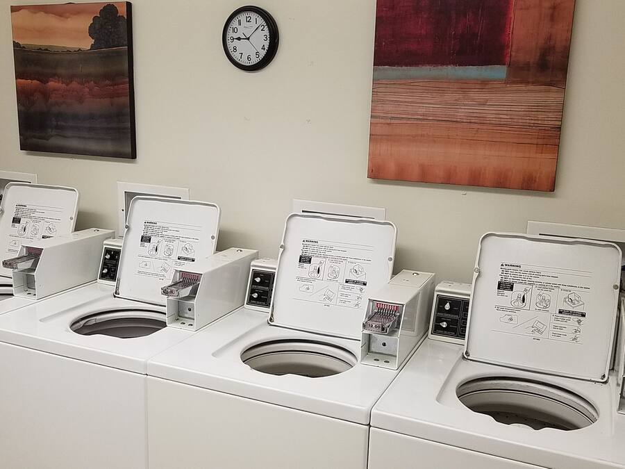 Uma fileira de sanitários públicos brancos, com pias individuais e secadores de mãos, cada um com uma etiqueta de aviso.
