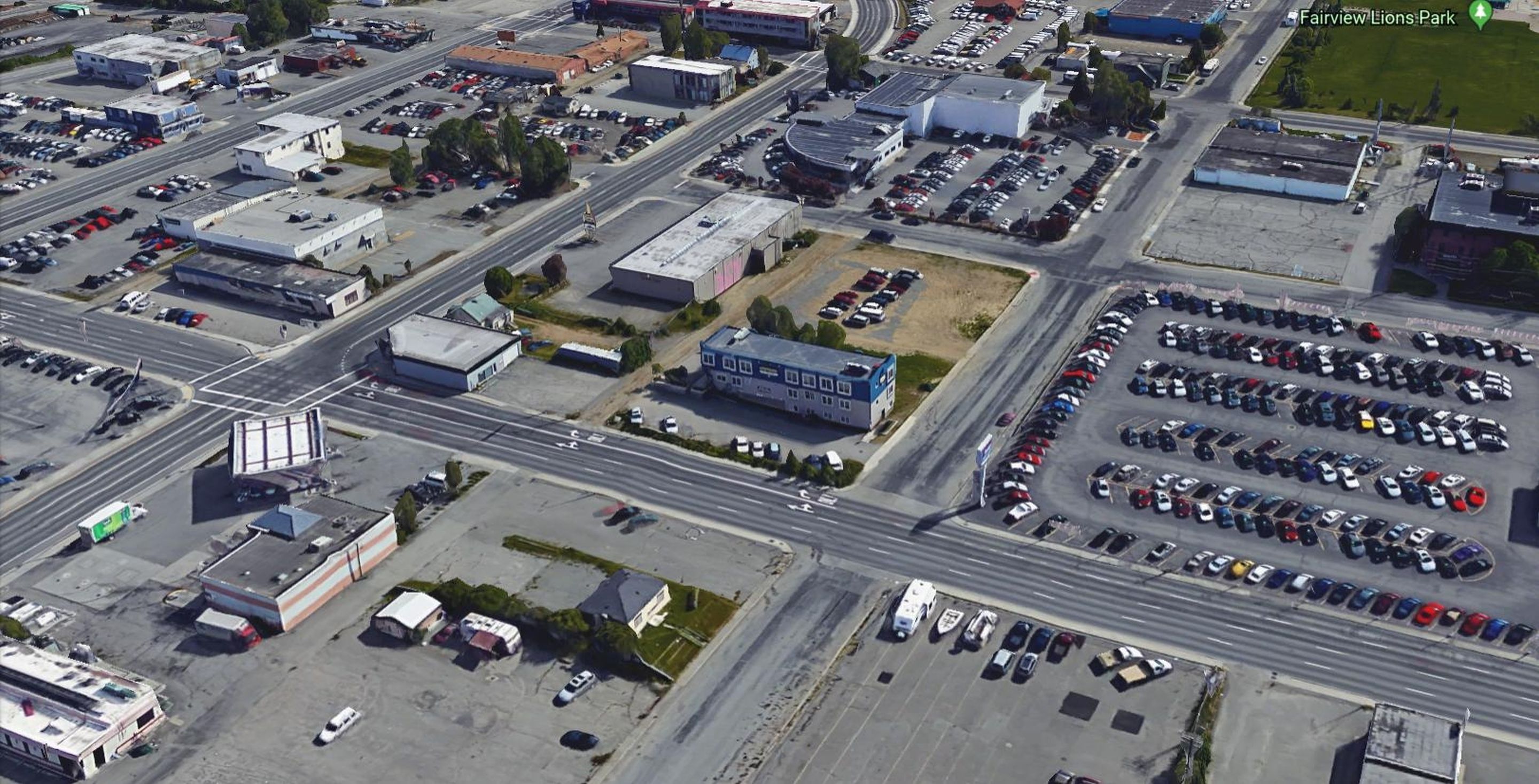 An aerial view of a commercial area with multiple parking lots, buildings, and roads.