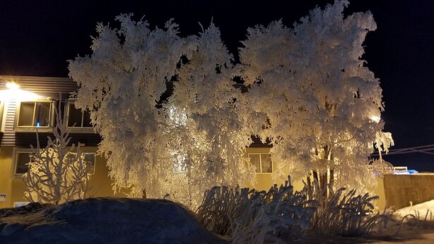 Un edificio con fachada nevada y una ventana iluminada.