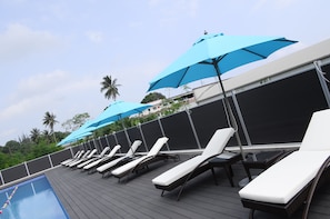 A poolside area with lounge chairs and blue umbrellas. - Luganvilla Business Hotel and Restaurant (Luganville)