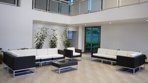 Um hall amplo com teto alto, área de estar em dois níveis e grandes janelas.