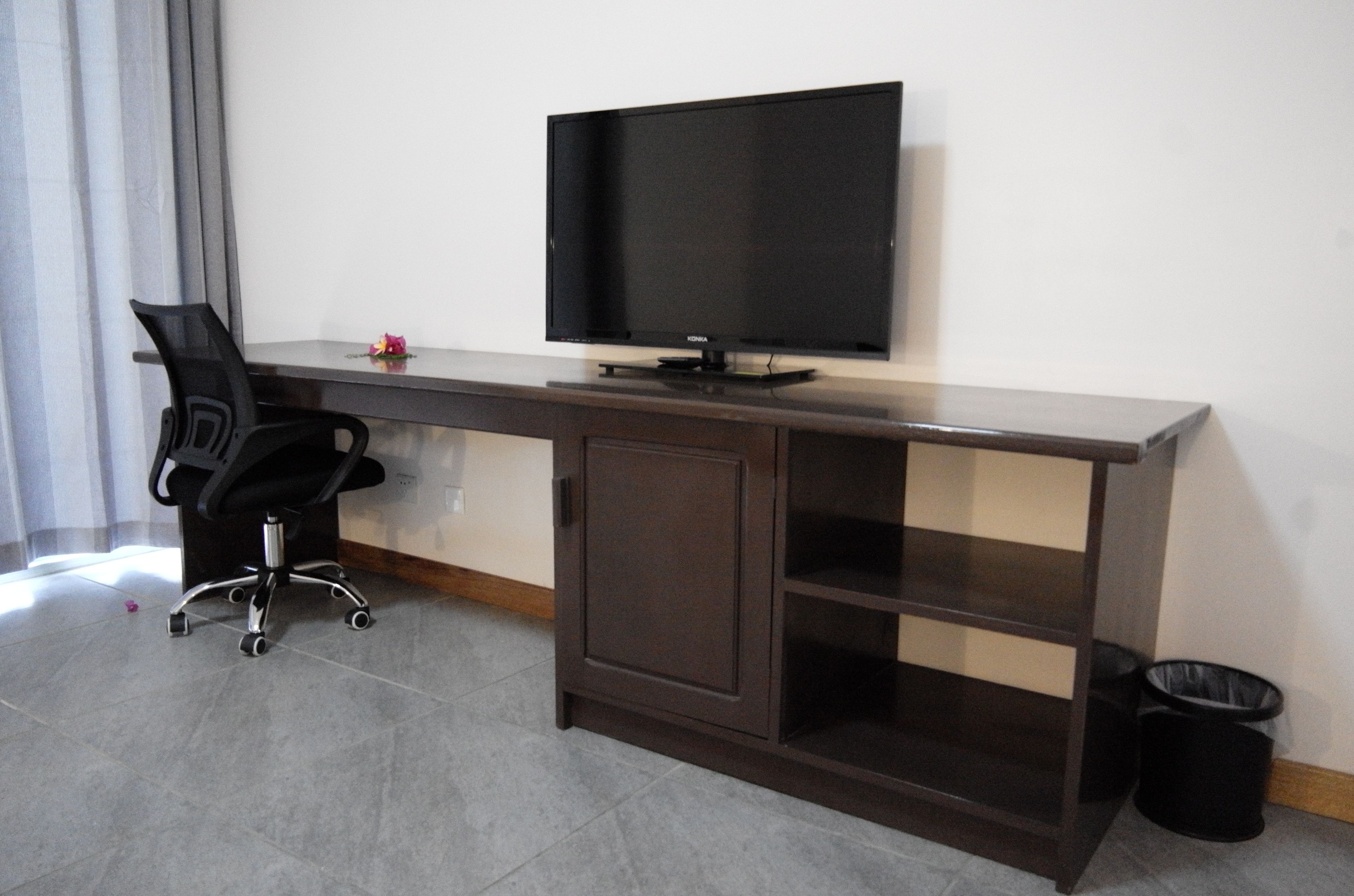 Un escritorio moderno con una televisión de pantalla plana, una silla de oficina negra y un archivador con estantes.