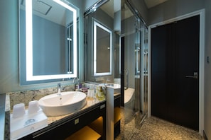 A modern bathroom with a large mirror, two sinks, and a glass shower enclosure.
