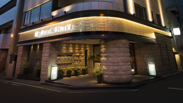 A multi-story hotel with a modern design, featuring a prominent entrance with a stone facade and illuminated signage. - Hotel Times - Adults Only (Tokyo)