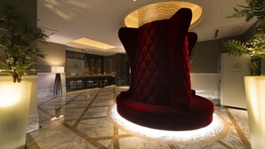A modern lobby with a central red velvet chair, marble flooring, and ambient lighting. - Hotel Times - Adults Only (Tokyo)
