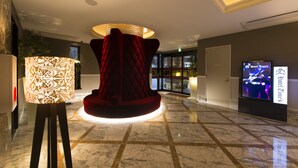 A lobby with a central red velvet chair, a patterned floor lamp, and a digital screen displaying hotel information. - Hotel Times - Adults Only (Tokyo)