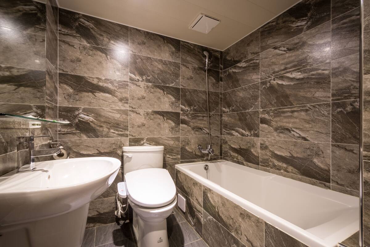 A modern bathroom with a freestanding bathtub, a double sink, and a toilet.