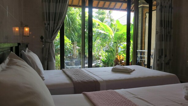 A room with two beds, a window with curtains, and a view of greenery outside. - Sea Hua Ha Ha - Hostel (Tulamben)