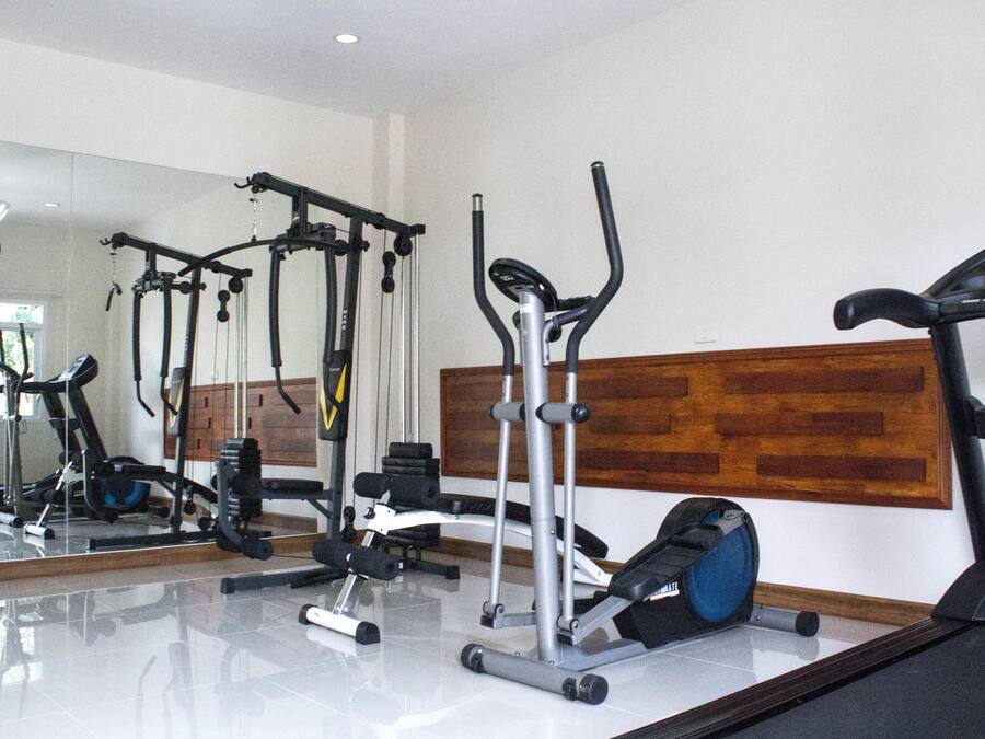 Een sportschool met diverse fitnessapparaten, waaronder een loopband, elliptische trainer en krachttoestellen.