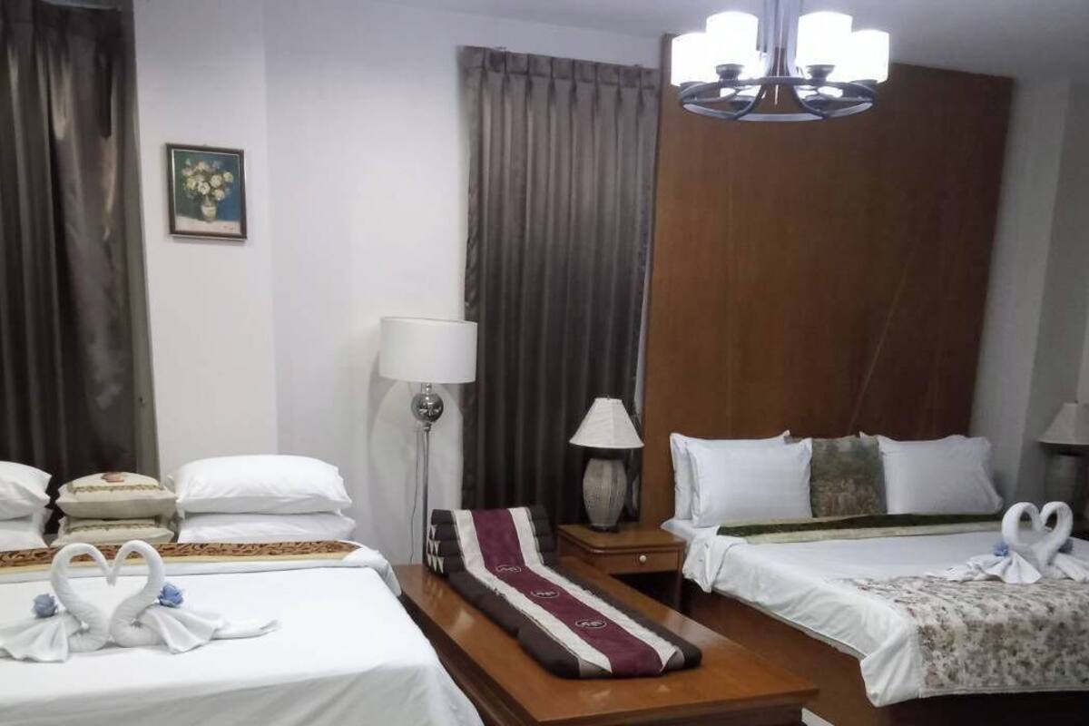 A hotel room with two beds, a wooden headboard, a chandelier, and a painting on the wall.