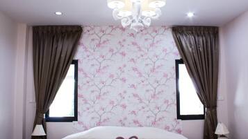 A bedroom with a bed, two bedside lamps, a chandelier, and floral wallpaper.