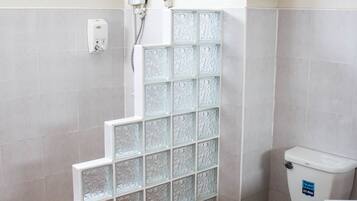 A bathroom with a glass block partition, a toilet, and a sink.