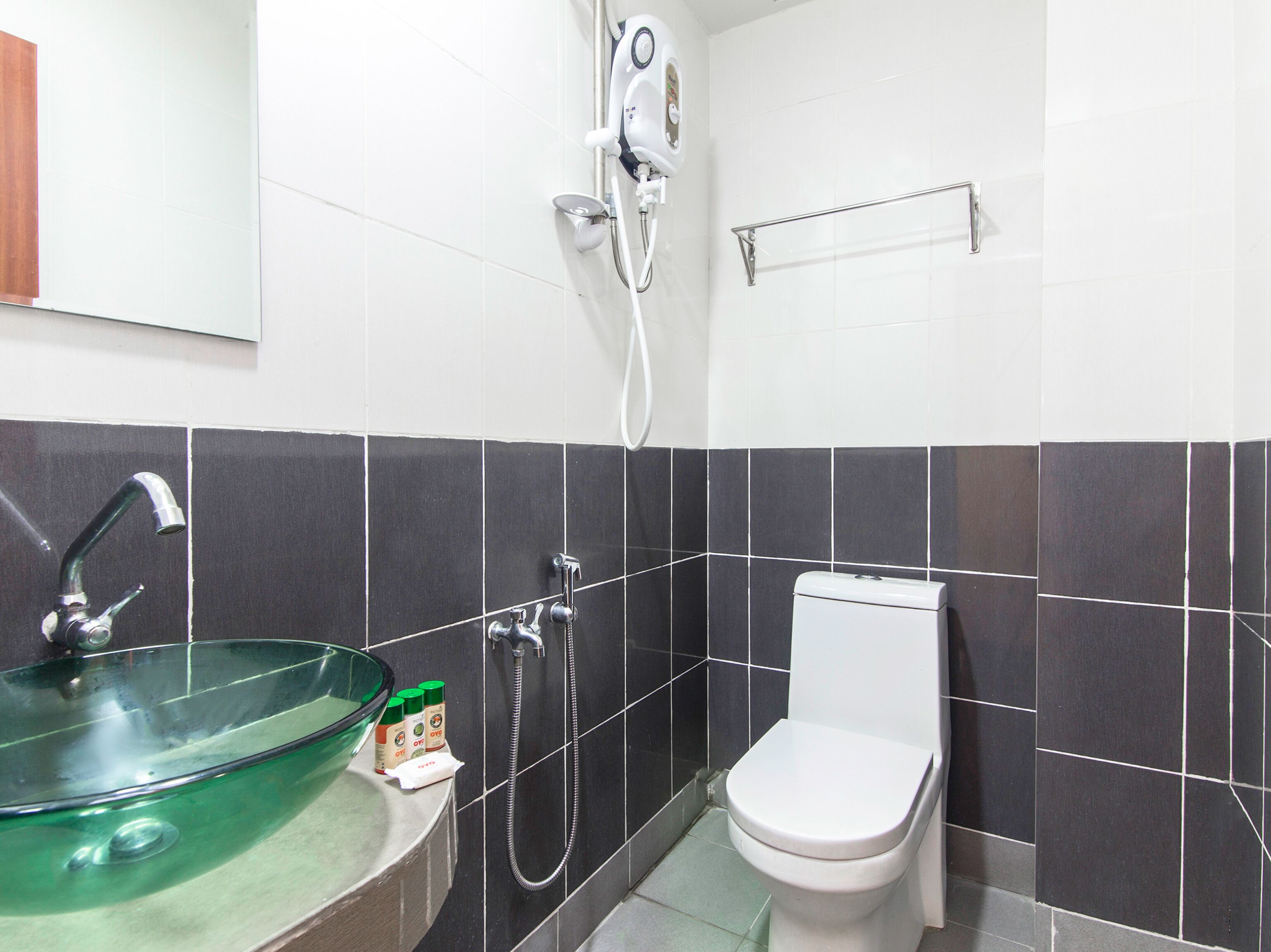 A bathroom with a glass bowl sink, a white toilet, and a handheld showerhead.