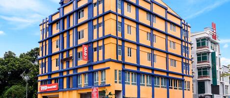 A multi-story hotel with a yellow facade and blue accents, featuring a prominent 'OYO Hotel' sign.