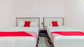 Camera d'albergo con due letti, ciascuno con copripiumino rosso e bianco, e un telefono sul comodino.