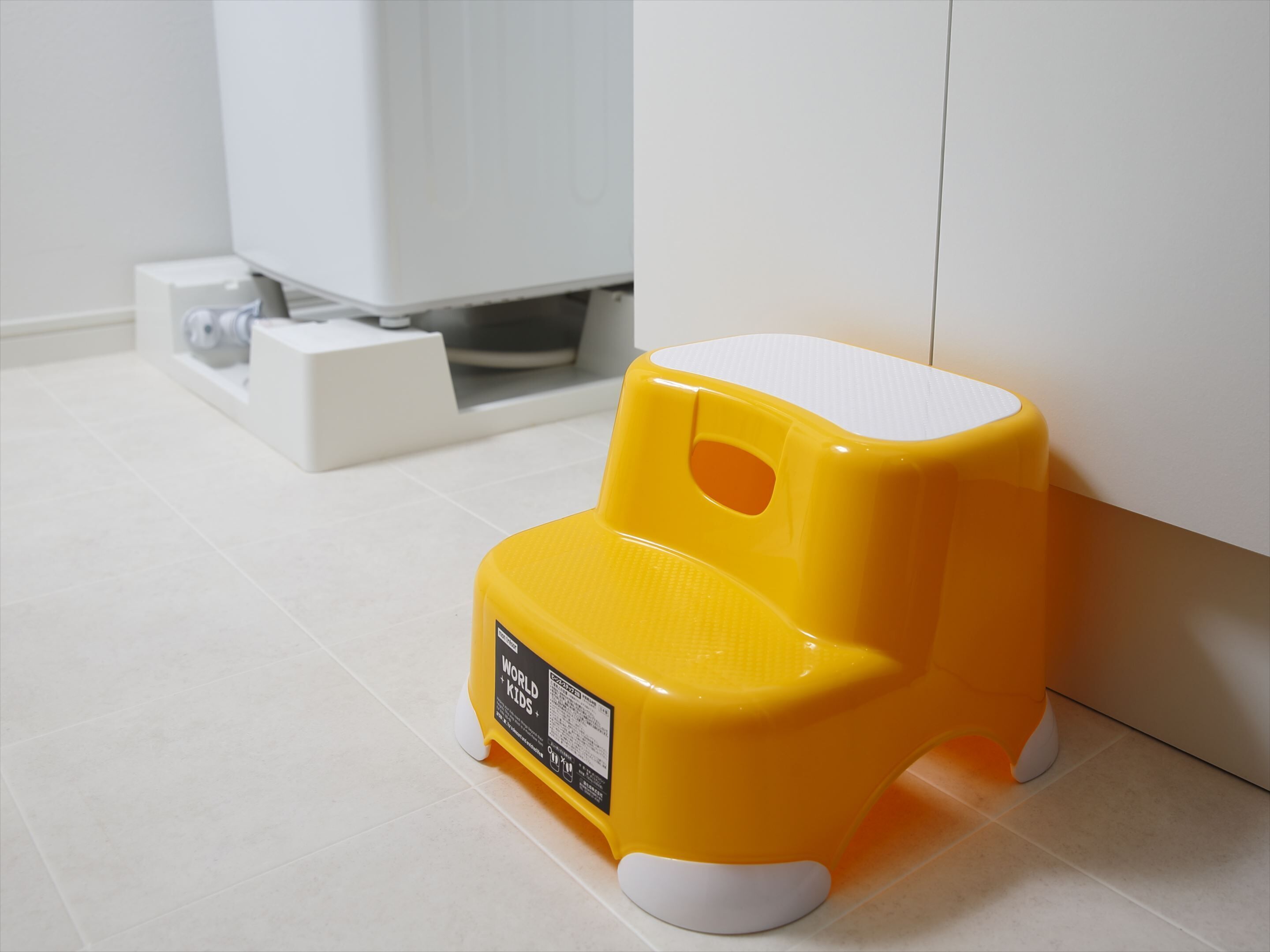 A small yellow and white step stool in a bathroom.