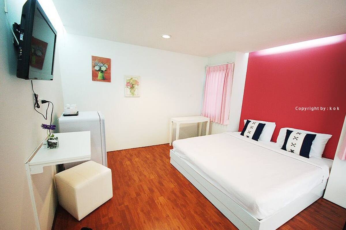 Un dormitorio con una cama, un escritorio, una silla, un televisor y una mesita.