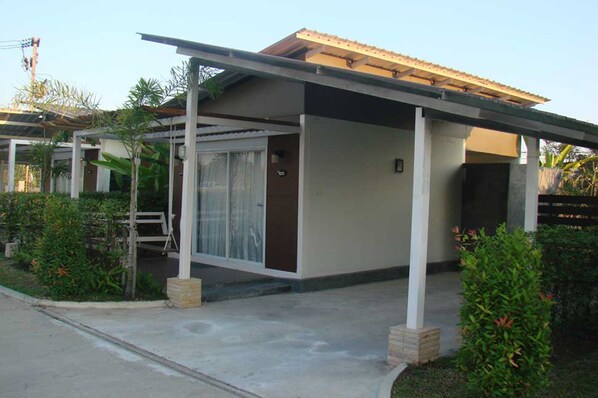 Un edificio moderno con un acceso cubierto, un pequeño jardín y un número de puerta visible.