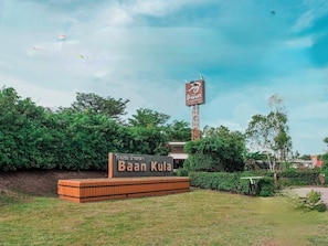 A sign for Baan Kula with a tall structure in the background.