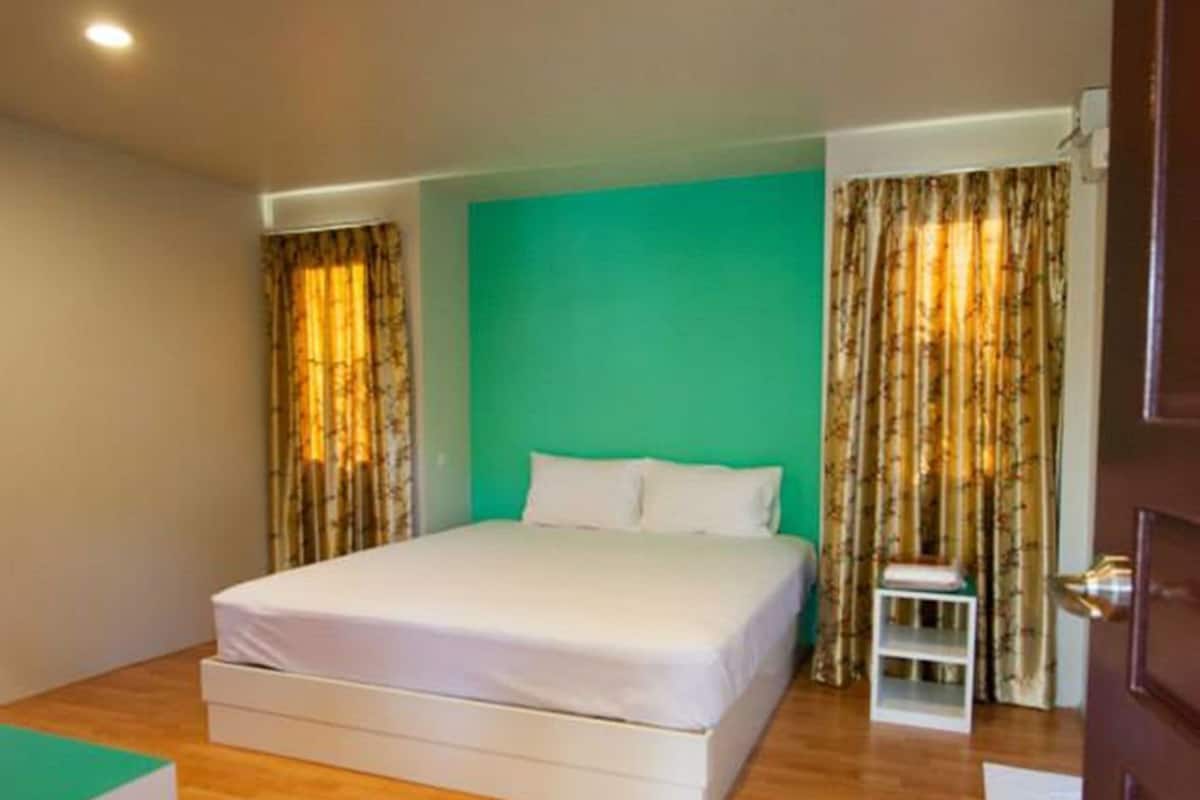 Um quarto com uma cama, uma mesinha e uma porta.