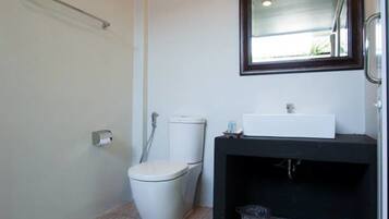 A modern bathroom with a white toilet, a black sink, and a mirror above it.