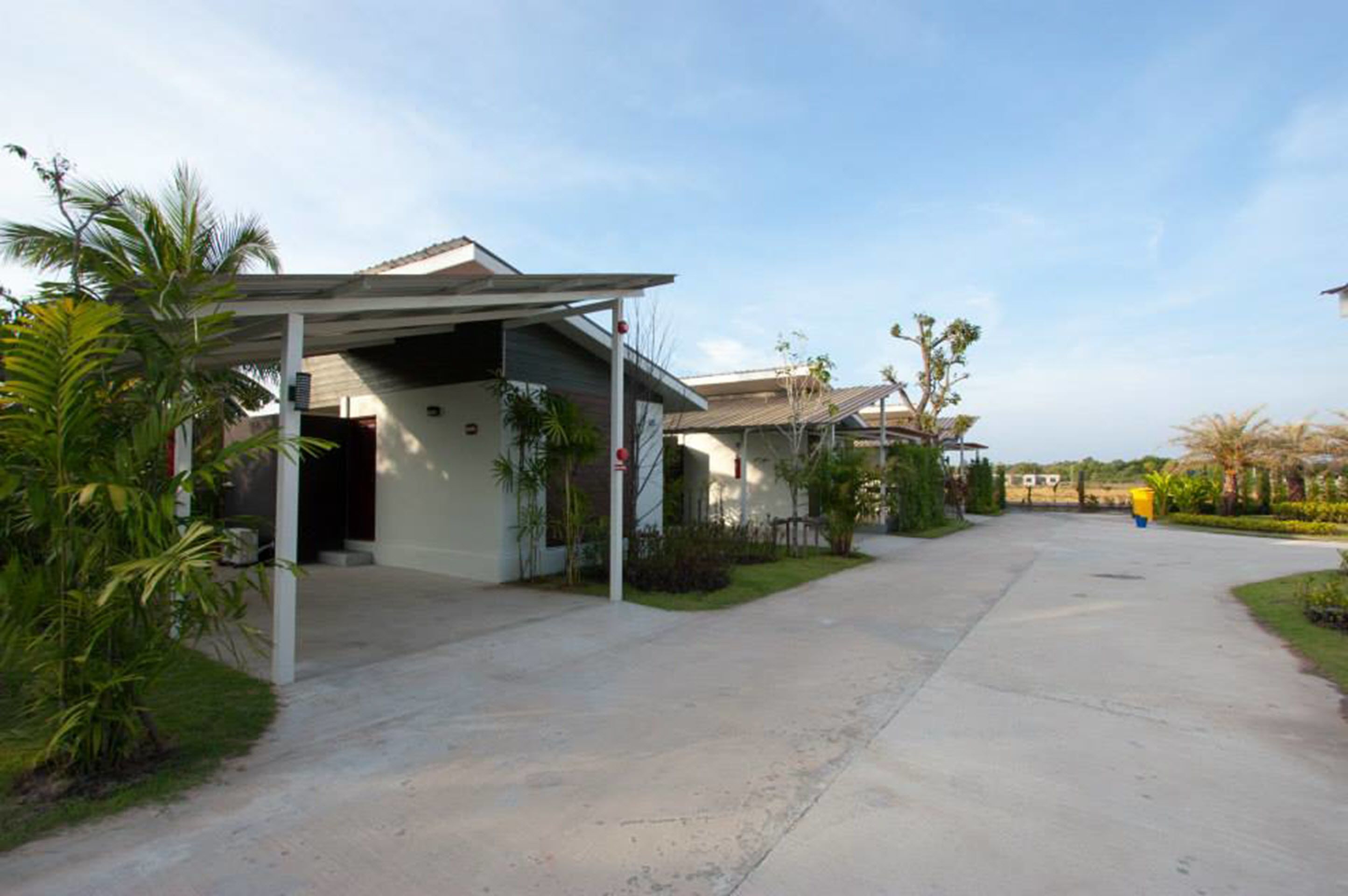 A residential area with houses, a covered driveway, and greenery.