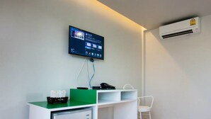 Un espacio de oficina pequeño y moderno con un escritorio, una silla y una televisión montada.