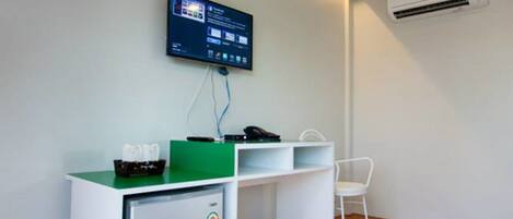 A small, modern office space with a desk, chair, and a mounted television.