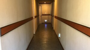 Un pasillo de hotel con pisos alfombrados, detalles de madera y una lámpara en el techo.