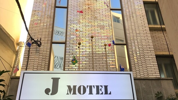 Un edificio con un cartel que dice "J Motel" y fachada de ladrillo.