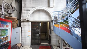 A hotel entrance with a tiled facade, a vending machine, and a staircase. - BaseInn Komagome Tokyo - Hostel (Tokyo)