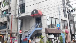 A multi-story building with a staircase leading to an upper floor. - BaseInn Komagome Tokyo - Hostel (Tokyo)