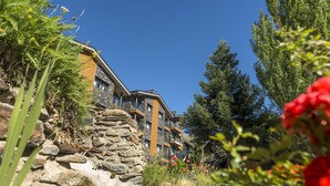 A multi-story building with balconies, surrounded by natural vegetation and a clear blue sky. - Pierre & Vacances Andorra Alba (El Tarter)