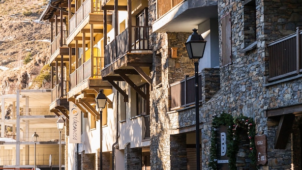 A multi-story building with wooden balconies and stone walls, featuring a sign for a restaurant. - Pierre & Vacances Andorra Alba (El Tarter)