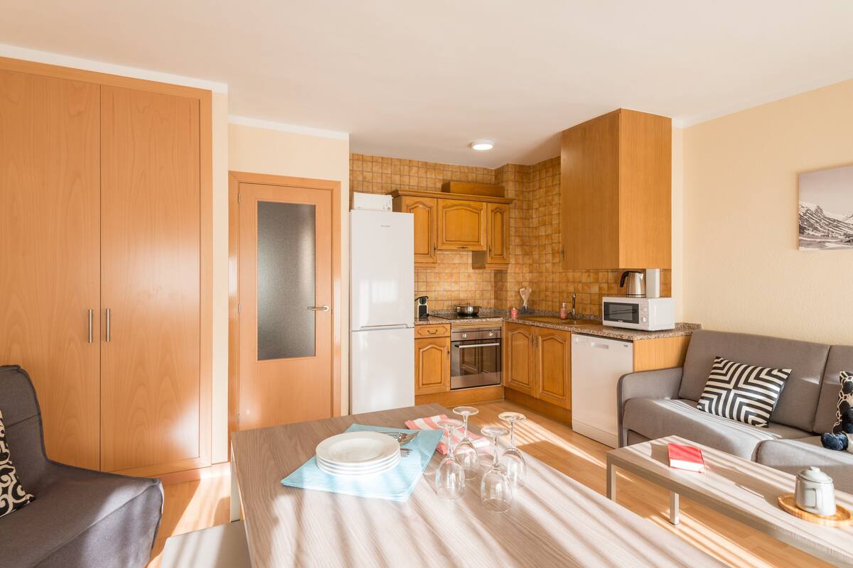 A compact living space with a kitchenette, a dining area, and a sofa.