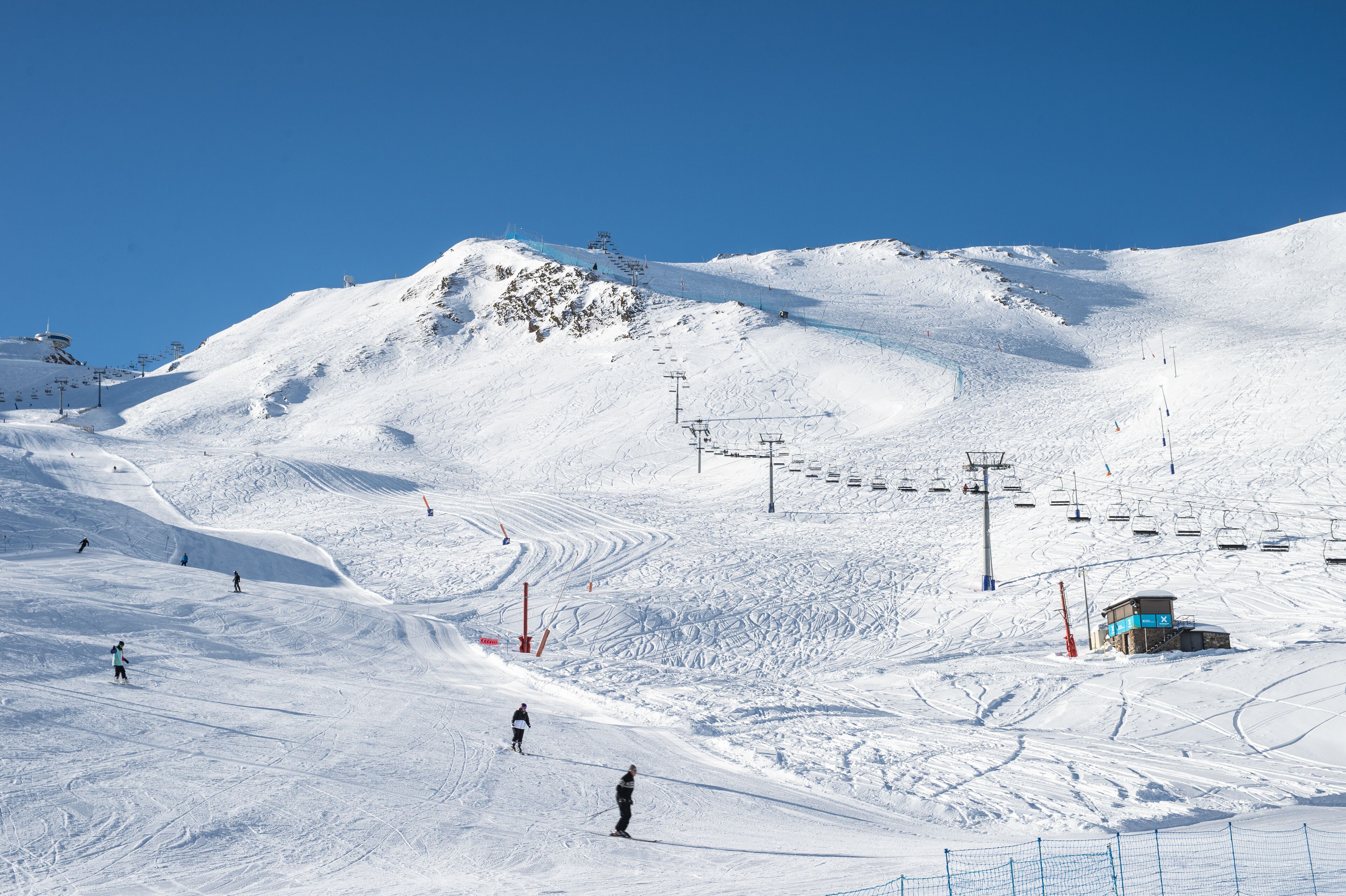 A snowy ski slope with ski lifts and a small building, likely a lodge or control center.