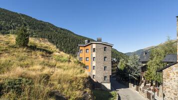 A mountain village with a narrow street, stone buildings, and a clear blue sky.