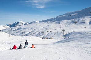 A snow-covered ski slope with a ski lift and a few skiers sitting on the ground. - Pierre & Vacances Andorra Alba (El Tarter)