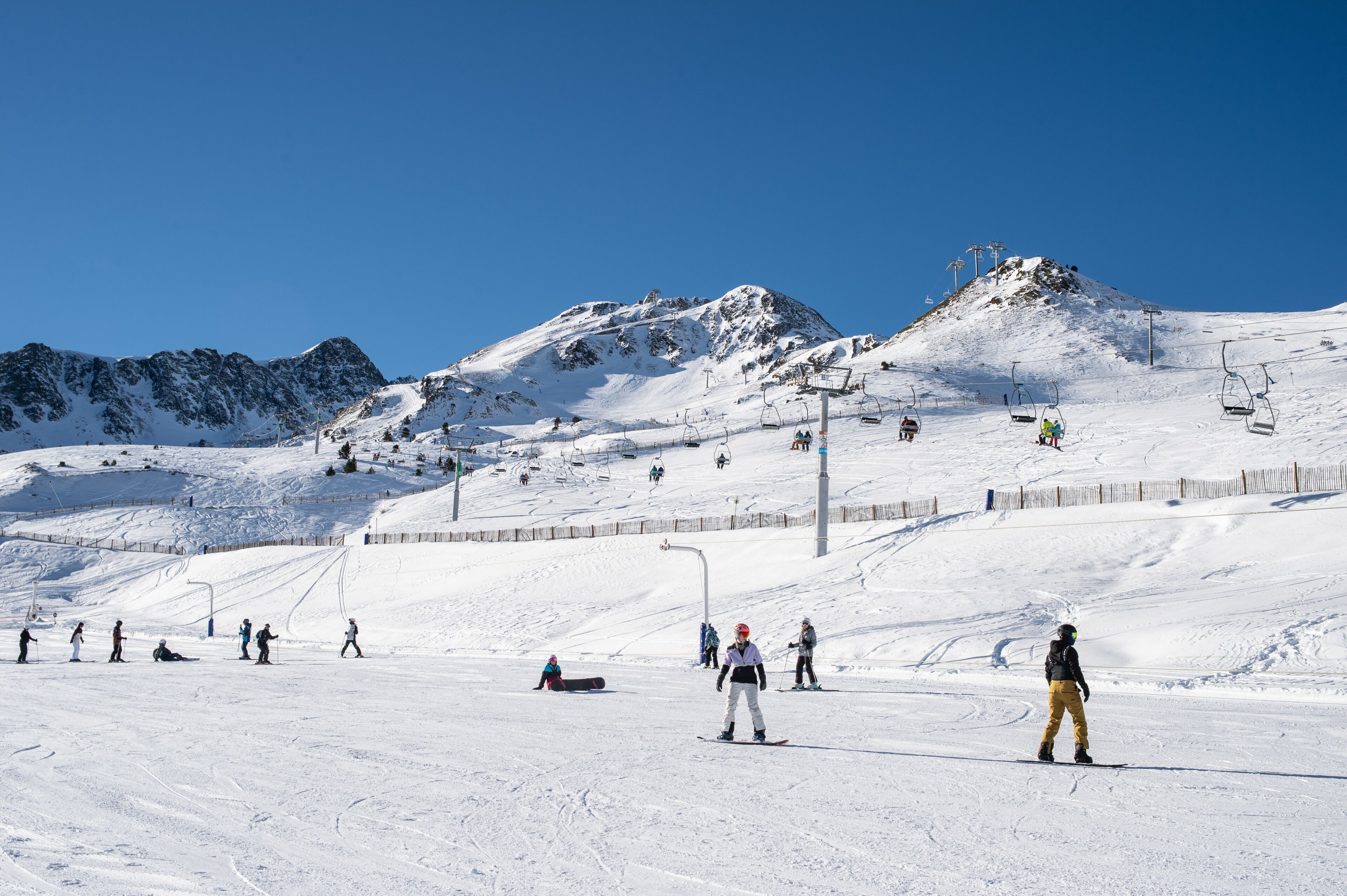 Pista de esquí cubierta de nieve con esquiadores y un telesilla.