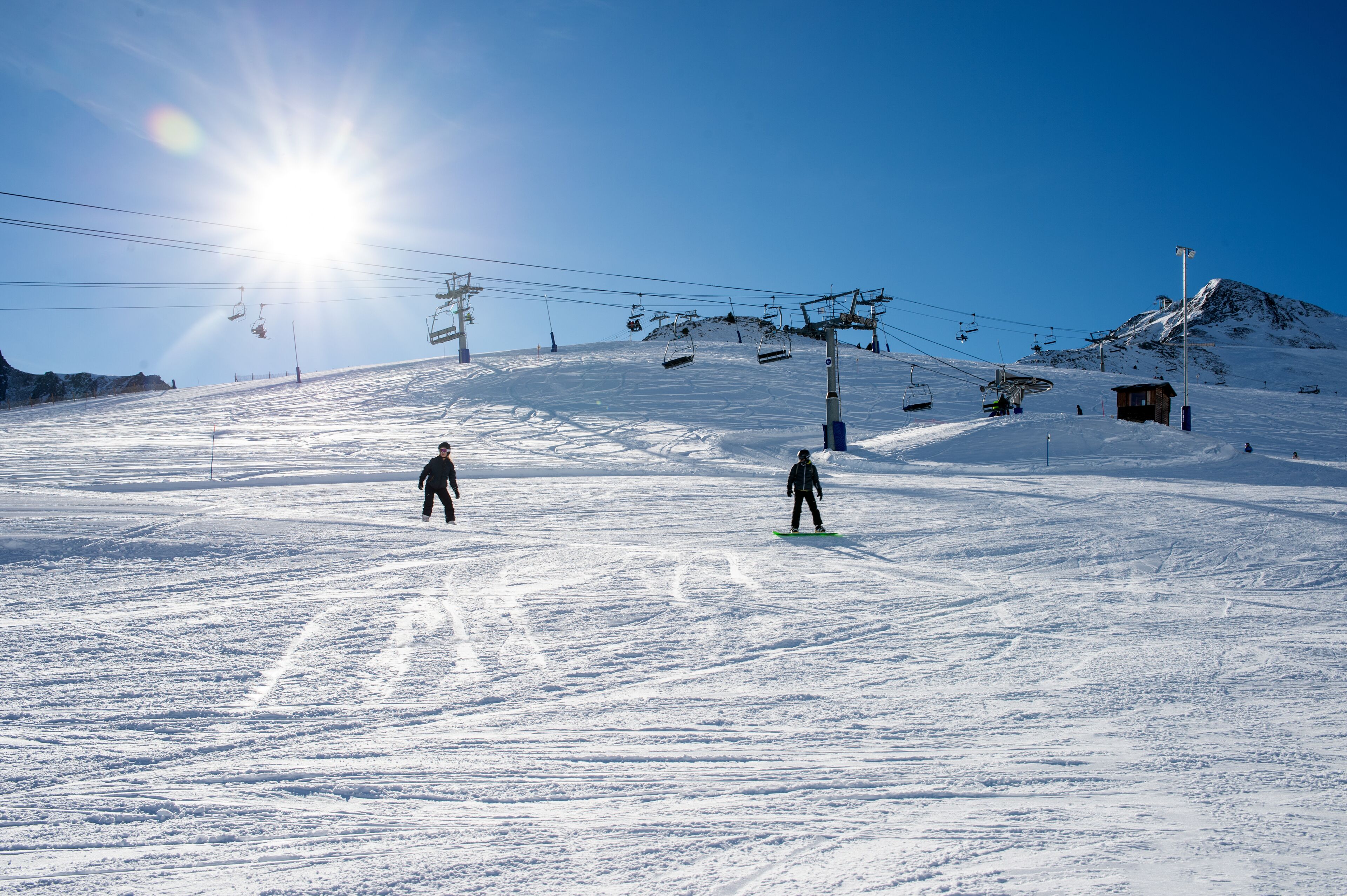 A snowy ski slope with ski lifts and a small cabin.