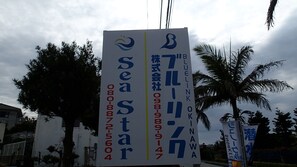 A vertical sign with text and logos, likely for a business or service. - Sea Blue (Onna)
