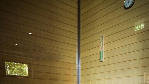 Interior de madera con un banco y un termómetro fijado a la pared.