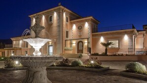 A large, well-lit building with a central fountain, surrounded by landscaped gardens and a paved courtyard. - Tenuta Esdra (Pontecorvo)