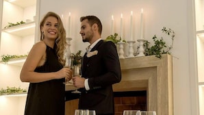 A couple toasting with champagne glasses at a dinner table set for two, with a fireplace and candles in the background. - Tenuta Esdra (Pontecorvo)