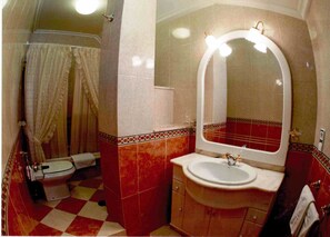 A bathroom with a checkered floor, a toilet, a sink, and a mirror with lights. - Hotel O Castelo (Cervo)