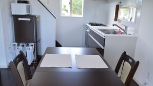 Une cuisine de taille réduite comprenant un réfrigérateur, une cuisinière, un évier et une table à manger avec des chaises.