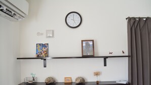 Une pièce avec deux étagères noires, une horloge, un cadre photo et une petite figurine.