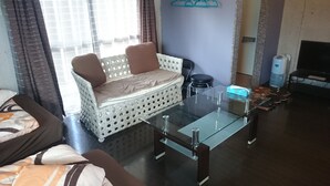 Un salon avec une table basse en verre, un canapé avec des coussins, un téléviseur et un distributeur d’eau.