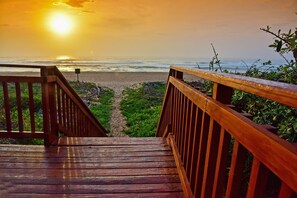 A wooden staircase leading to a beach with a sunset in the background. - La Lucia Sands (Umhlanga)