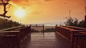 A wooden boardwalk leading to a beach with a sunset in the background.